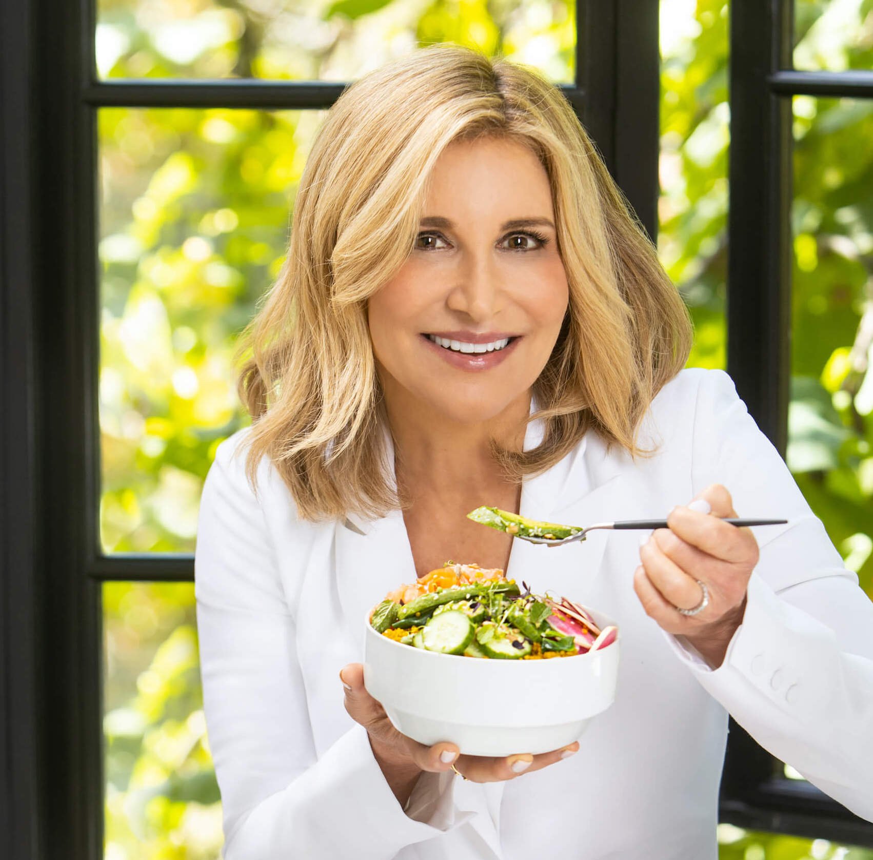Mujer sonriendo comiendo un bol de verduras