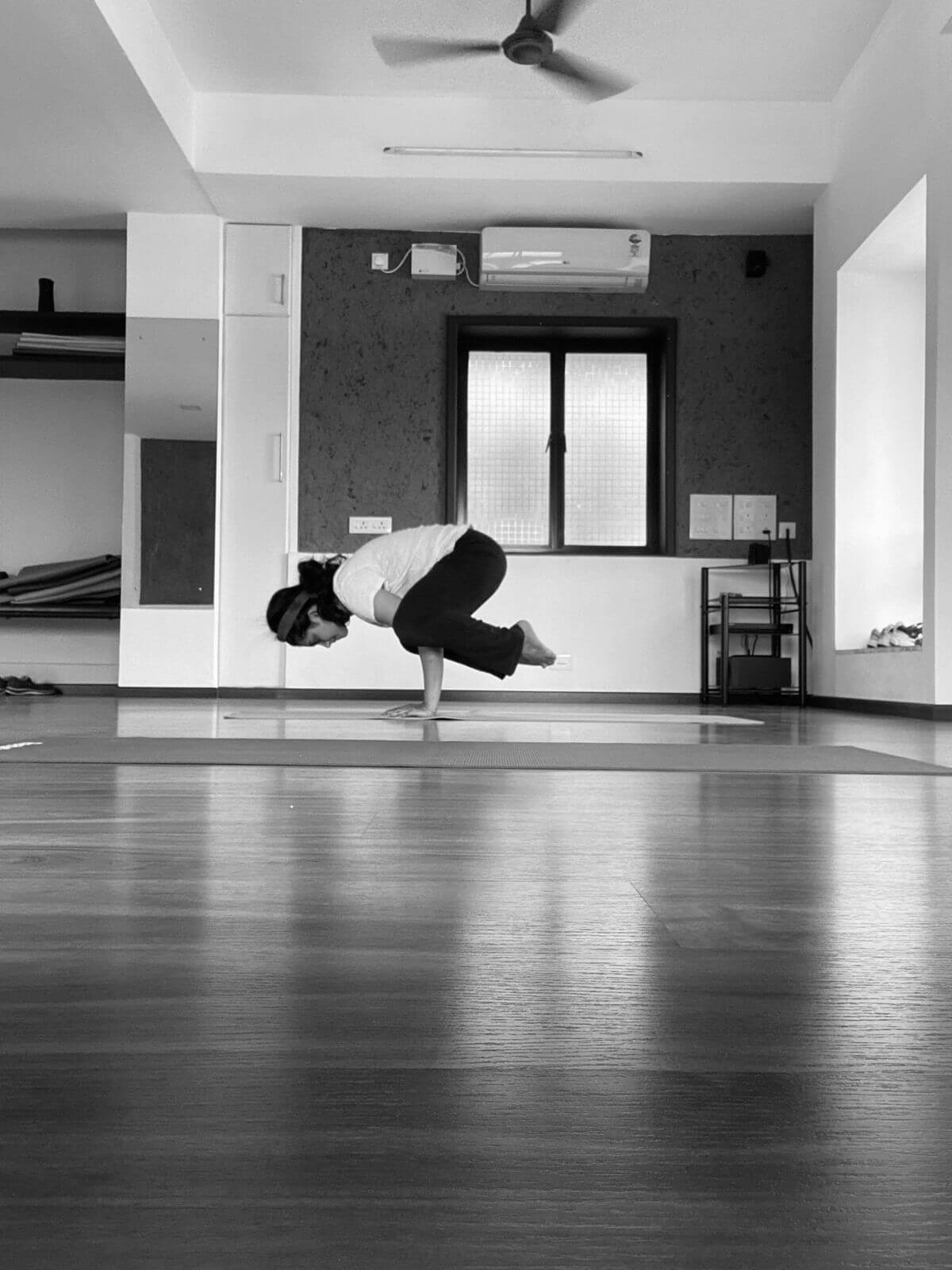 mujer haciendo la postura del cuervo sobre una esterilla de yoga
