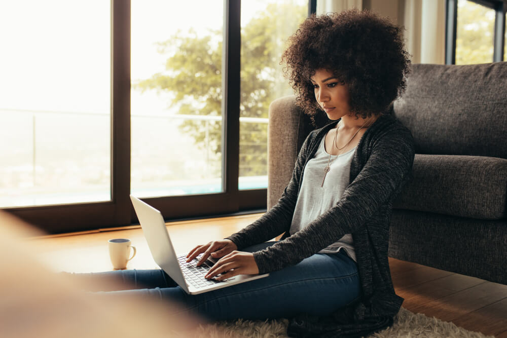 mujer negra sentada en el suelo con su ordenador
