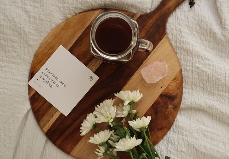Tarjeta de afirmación, café negro, flores y cristal sobre la cama