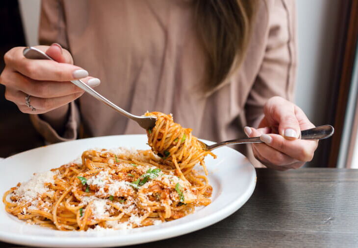 mujer girando espaguetis en un plato